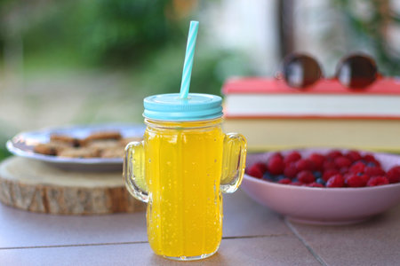 Straw hat, orange soda in the cactus shaped cup, bowl of fresh blueberreis and raspberries, plate of...