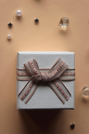 Small white present on neutral peachy background. Stars, pearls and beads in the background....
