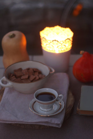 Vintage books, reading glasses, bowl of cookies, cup of tea or coffee, pumpkins and candle holder in...