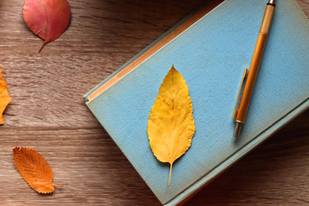 Cup of tea or coffee, plate with cookies and chocolate, dried oranges, bowl of grapes, vintage books, pumpkins and autumn leaves on the table. Autumnal hygge. Top view.の写真素材