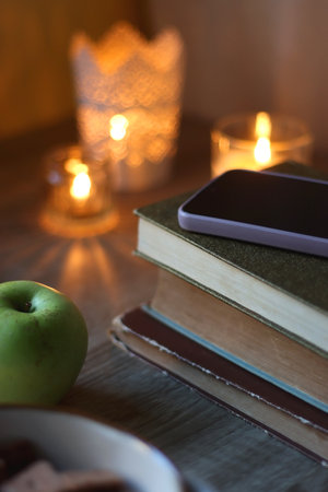 Vintage books, e-reader, pen, reading glasses, phone, cup of tea or coffee, bowl of cookies, green...