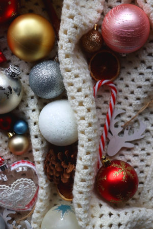 Various colorful Christmas ornaments, small presents and seasonal spices on white knitted blanket....