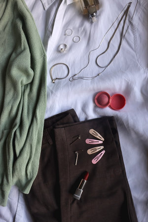 Pastel green cardigan, white shirt, gray trousers, black loafers, various silver jewelry, perfume...
