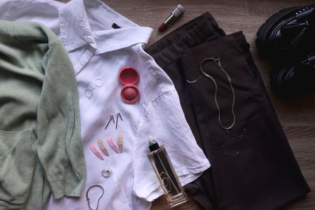 Pastel green cardigan, white shirt, gray trousers, black loafers, various silver jewelry, perfume...