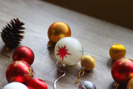 Pine cones and red, golden and white Christmas ornaments on wooden background. Selective focus.