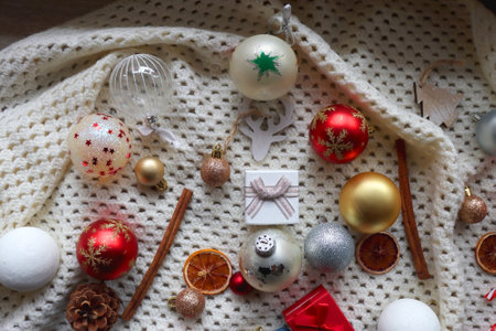 Various colorful Christmas ornaments, small presents and seasonal spices on white knitted blanket. Top view.の写真素材