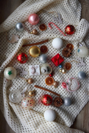 Various colorful Christmas ornaments, small presents and seasonal spices on white knitted blanket. Top view.の写真素材