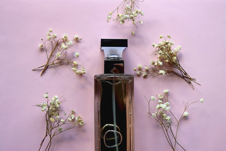 Unrecognizable perfume bottle and gypsophila flowers on pastel pink background. Flat lay.の写真素材