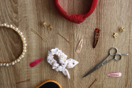 Wooden hairbrush, scissors and various headbands, hair clips and scrunchies on wooden background. Flat lay.の写真素材