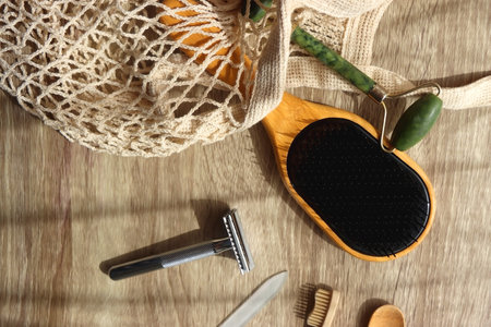 Crochet bag, wooden hairbursh, face roller, reusable razor, glass nail file, wooden toothbrush and wooden spoon on wooden background. Various zero waste products. Flat lay.の写真素材