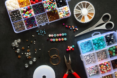 Colorful beads and various jewelry making supplies on dark background. Letter beads spelling JEWELRY MAKING. Top view.の写真素材