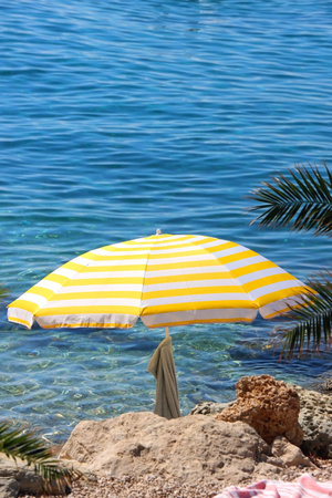 Colorful parasol on the beaach, by the sea. Sunny summer day. Selective focus.の写真素材