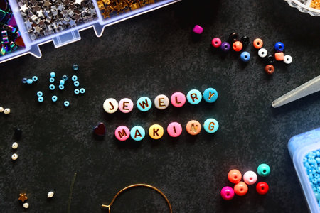 Colorful beads and various jewelry making supplies on dark background. Letter beads spelling JEWELRY...