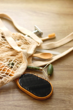 Crochet bag, wooden hairbursh, face roller, reusable razor, glass nail file, wooden toothbrush and wooden spoon on wooden background. Various zero waste products. Selective focus.の写真素材