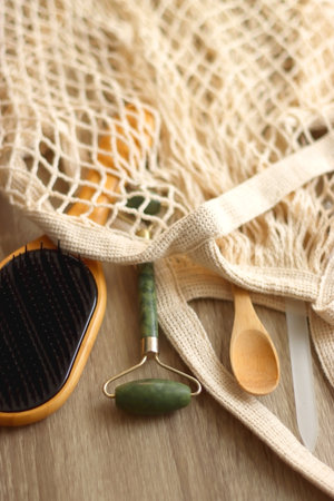 Crochet bag, wooden hairbursh, face roller, reusable razor, glass nail file, wooden toothbrush and wooden spoon on wooden background. Various zero waste products. Selective focus.の写真素材