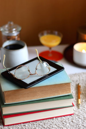 Cup of tea or coffee, stack of books, e-reader, glasses, various cookies, almonds, orange juice and...