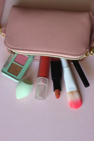 Pink make up bag with various beauty products. Pink background, selective focus.の写真素材