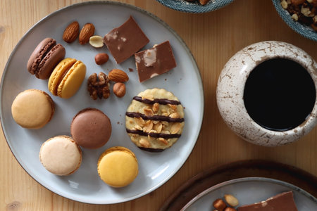 Cup of tea or coffee, cookies, macaroons, chocolate, various nuts and cocoa powder on wooden table. Top view.の写真素材