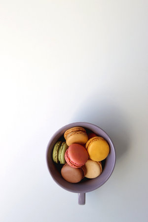 Purple cup filled with pastel macarons on white background. Top view.の写真素材