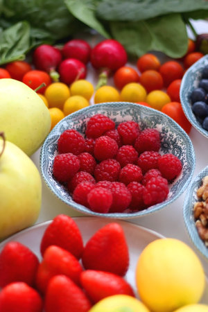 Apples, lemons, bananas, berries, carrots, leek, tomatoes, radishes, spinach and various nuts on white background. Healthy seasonal fruit and vegetable. Selective focus.の写真素材