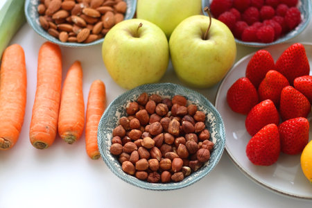 Apples, lemons, bananas, berries, carrots, leek, tomatoes, radishes, spinach and various nuts on white background. Healthy seasonal fruit and vegetable. Selective focus.の写真素材