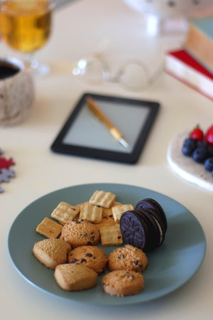 Colorful jigsaw puzzle pieces, books, tablet, glasses, cookies, berries, cup of tea or coffee, glass...