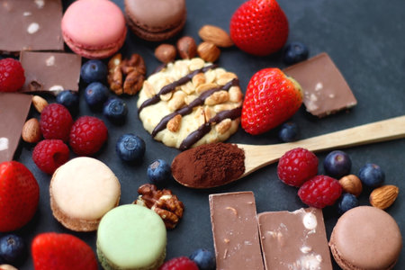 Macarons, chocolate, cookies, berries and various nuts on dark blue background. Selective focus.の写真素材