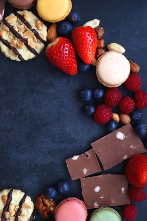 Macarons, chocolate, cookies, berries and various nuts on dark blue background. Top view.の写真素材