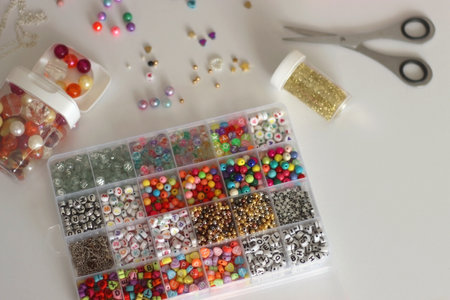 Making friendship bracelets with letter beads. Jewelry making supplies on the table. Selective...
