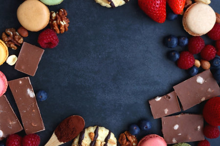 Macarons, chocolate, cookies, berries and various nuts on dark blue background. Top view.の写真素材