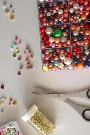 Colorful beads, letter beads, threads and other jewelry making supplies on white background. Making friendship bracelets concept. Flat lay.の写真素材