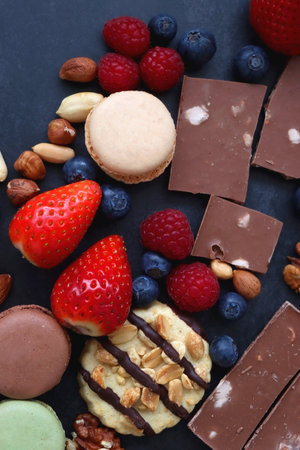 Macarons, chocolate, cookies, berries and various nuts on dark blue background. Top view.の写真素材