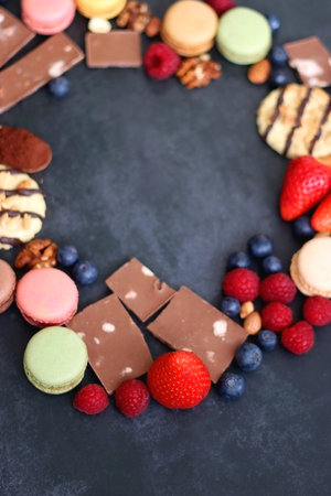 Macarons, chocolate, cookies, berries and various nuts on dark blue background. Selective focus.の写真素材