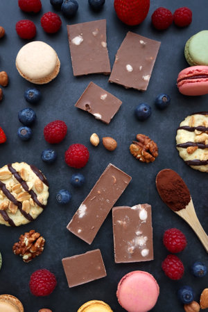 Macarons, chocolate, cookies, berries and various nuts on dark blue background. Top view.の写真素材