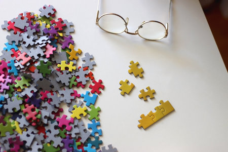 Colorful jigsaw puzzle pieces, cup of tea or coffee, eyeglasses and fresh berries for snacking....