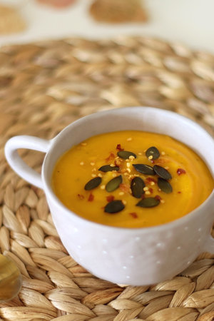 Pumpkin and potato creamy soup, bowl of grapes, jars of nuts and autumn leaves on the table. Selective focus.の写真素材