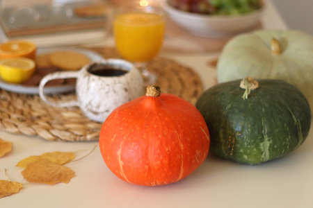 Pumpkins, various food and drinks, fall decorations, books and candles on the table. Fall hygge at home. Selective focus.の写真素材