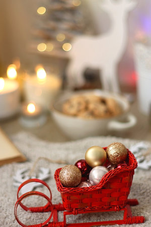 Various Christmas decorations, lit candles, cup of tea or coffee, cookies, books, presents and soft blanket on the table. Holiday hygge at home. Selective focus.の写真素材