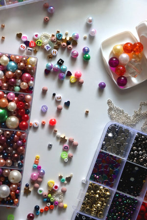 Colorful beads, letter beads, threads and other jewelry making supplies on white background. Making friendship bracelets concept. Flat lay.の写真素材