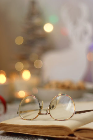Various Christmas decorations, lit candles, cup of tea or coffee, cookies, books, presents and soft blanket on the table. Holiday hygge at home. Selective focus.の写真素材