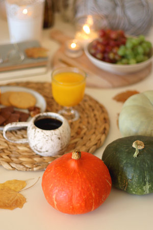 Pumpkins, various food and drinks, fall decorations, books and candles on the table. Fall hygge at home. Selective focus.の写真素材