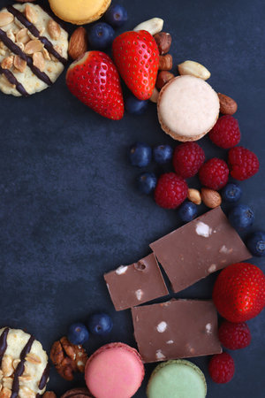 Macarons, chocolate, cookies, berries and various nuts on dark blue background. Top view.の写真素材