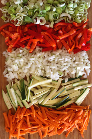 Chopped leek, red pepper, onion, zucchini and carrot on the chopping board. Cooking and meal prepping at home. Flat lay.の写真素材