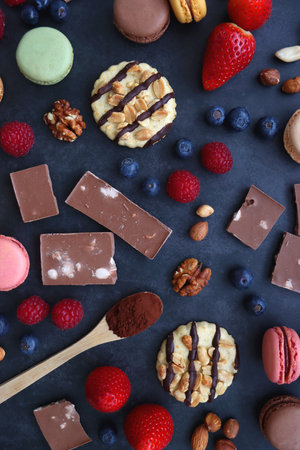 Macarons, chocolate, cookies, berries and various nuts on dark blue background. Top view.の写真素材