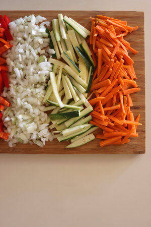 Chopped leek, red pepper, onion, zucchini and carrot on the chopping board. Cooking and meal prepping at home. Flat lay.の写真素材