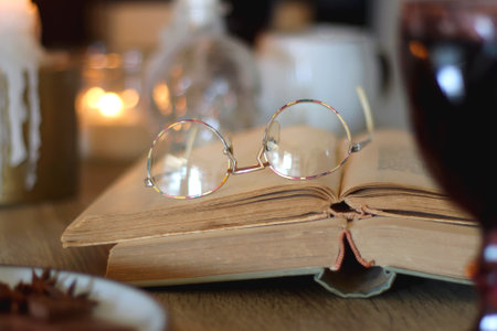 Books, lit candles, red wine, snacks and various decoration on the table. Dark academia or Halloween concept. Selective focus.の写真素材