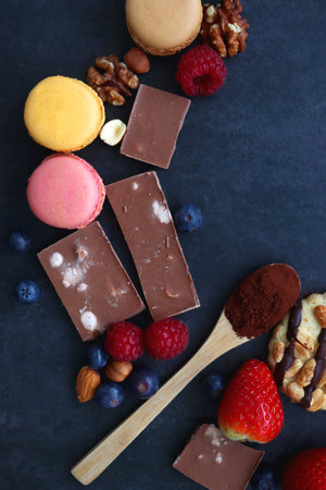 Macarons, chocolate, cookies, berries and various nuts on dark blue background. Top view.の写真素材