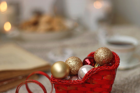 Various Christmas decorations, lit candles, cup of tea or coffee, cookies, books, presents and soft blanket on the table. Holiday hygge at home. Selective focus.の写真素材