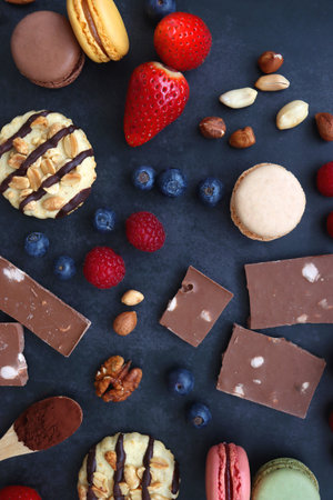Macarons, chocolate, cookies, berries and various nuts on dark blue background. Top view.の写真素材