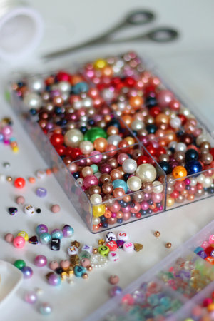 Colorful beads, letter beads, threads and other jewelry making supplies on white background. Making friendship bracelets concept. Selective focus.の写真素材